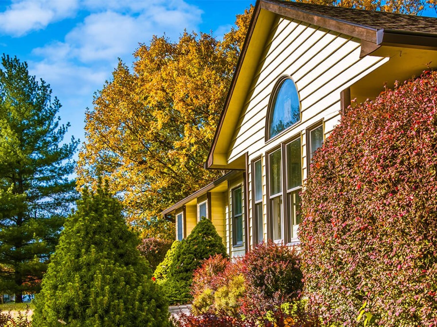 Front of house surrounded by fall trees.