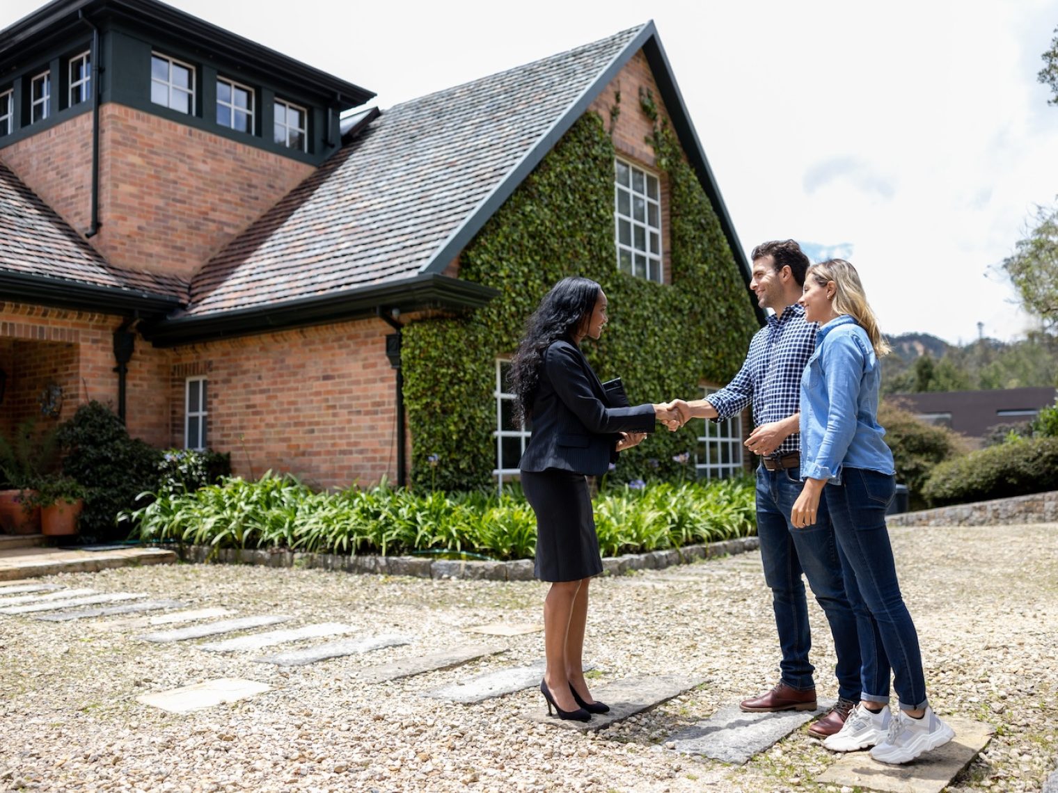 Real estate agent meeting couple outside of a home.