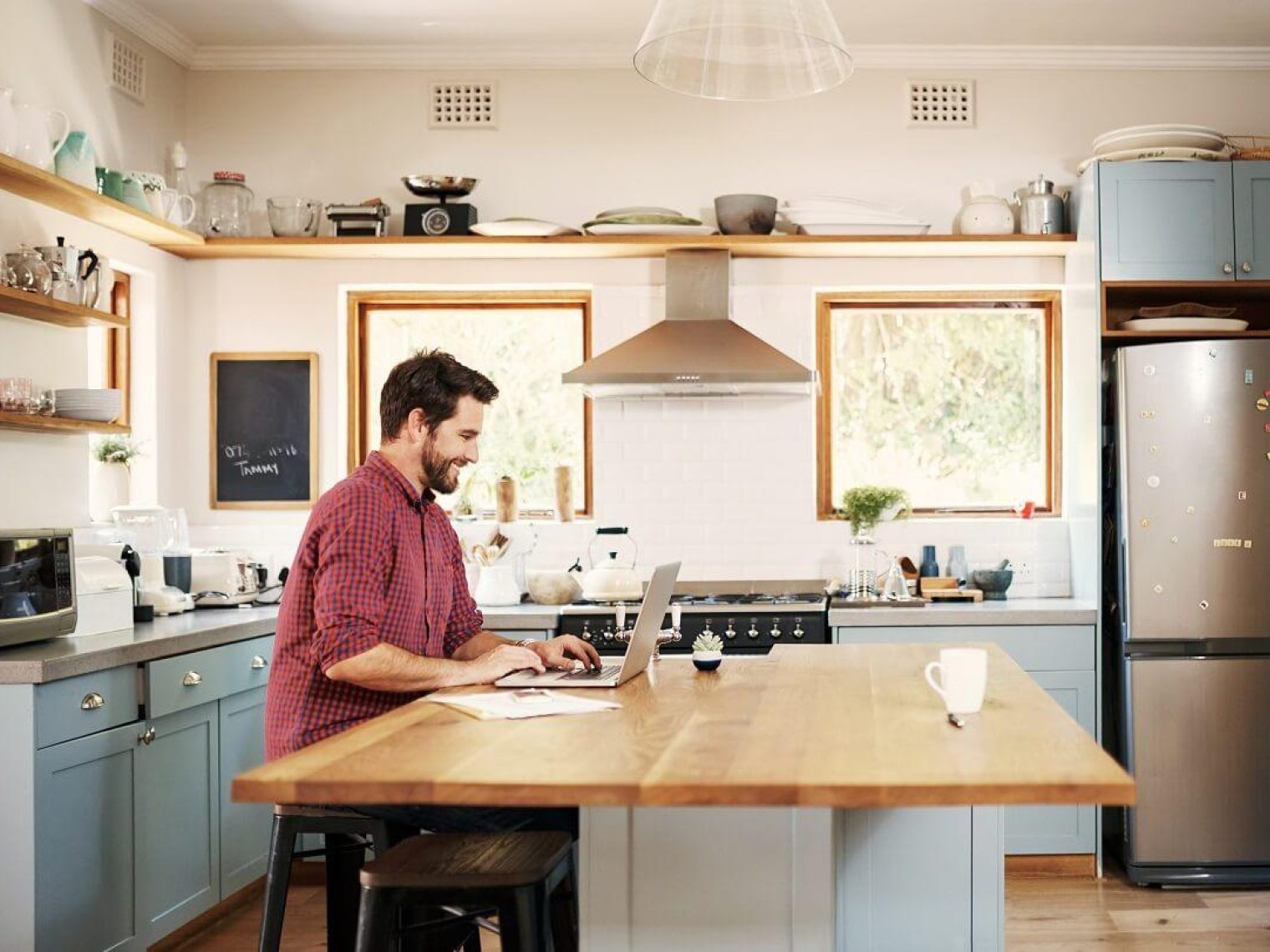 Man working on laptop on kitchen island.