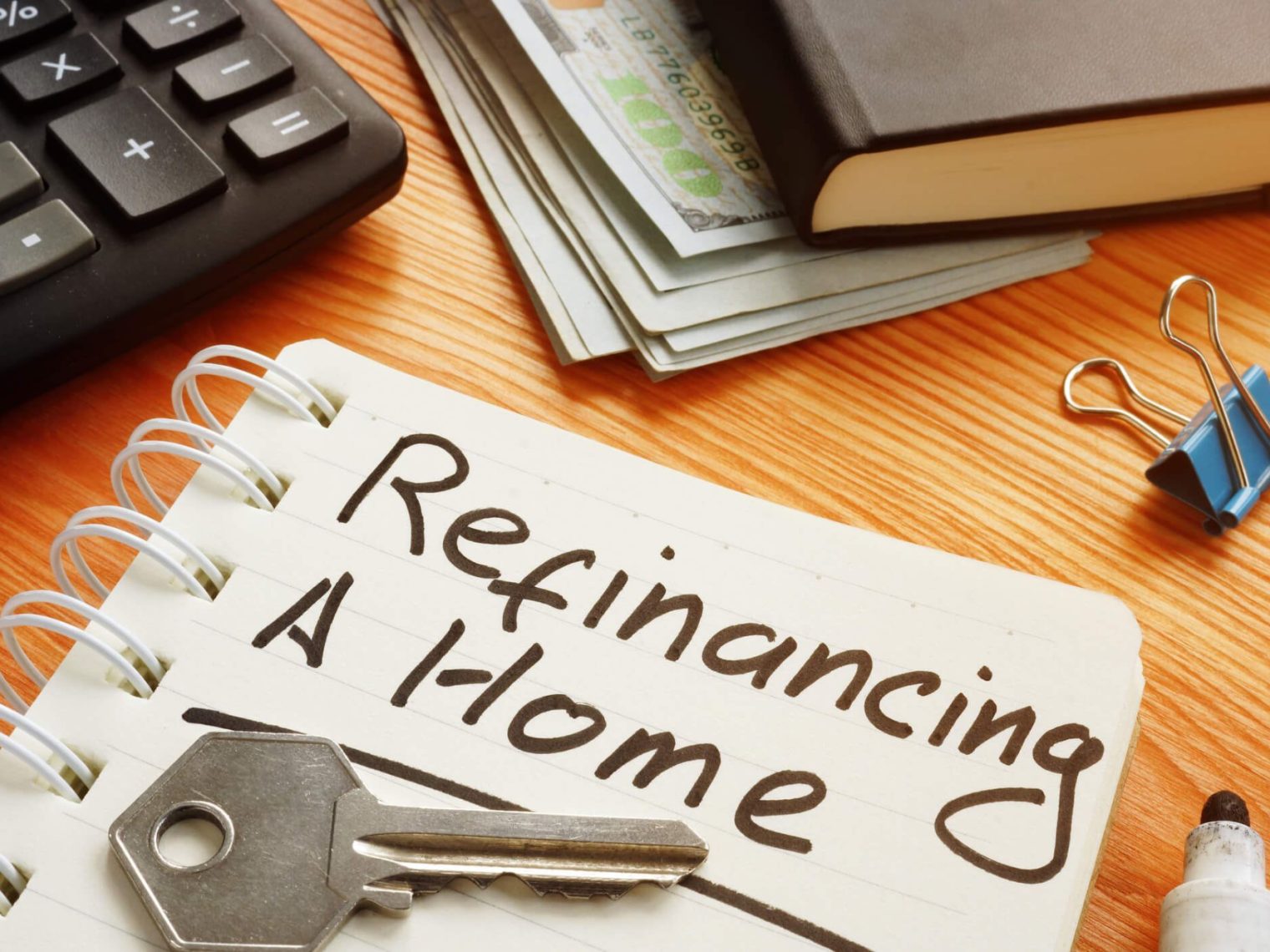 Notebook on a desk that says "Refinancing a home."