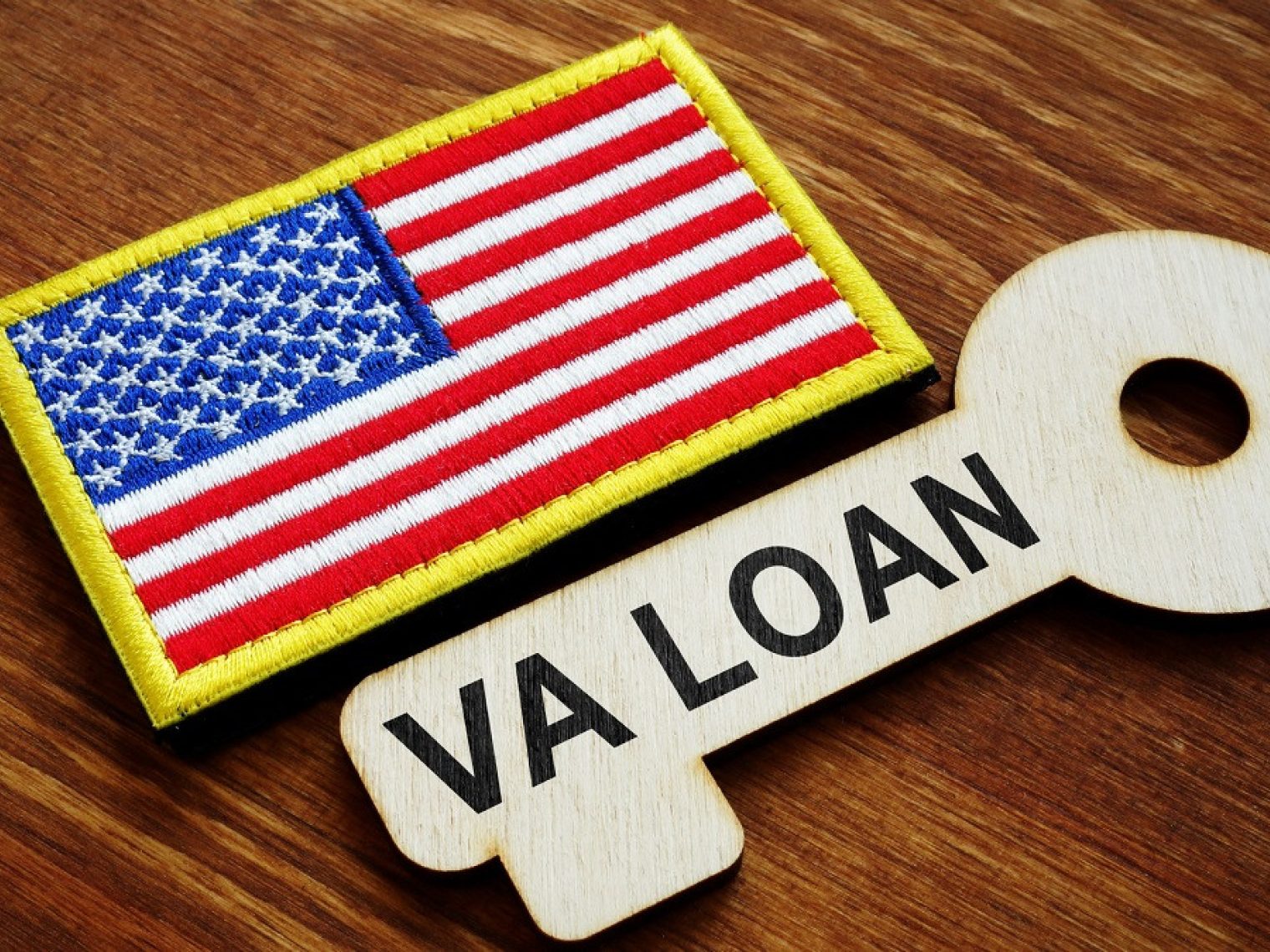 Close up of American flag patch next to a wood-carved key that says "VA Loan".