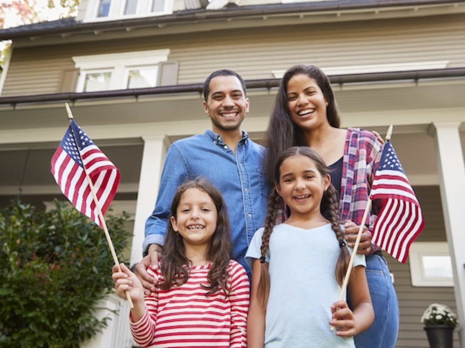 Family holding American flags outside of home.