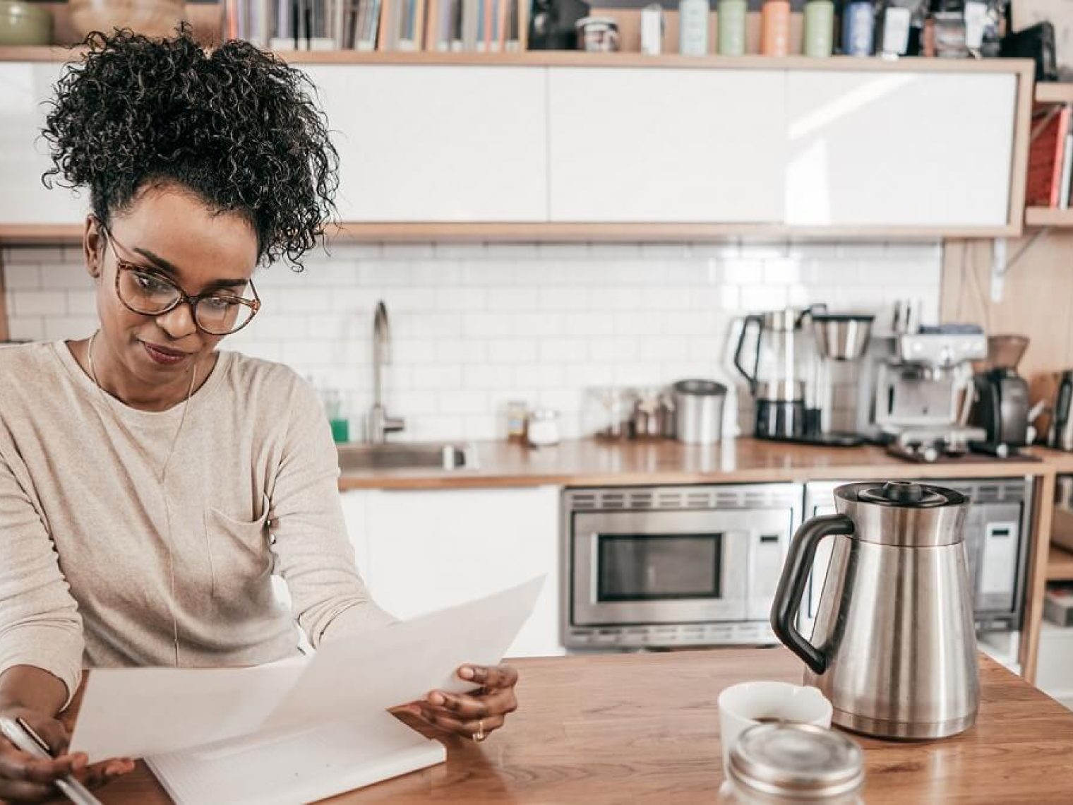 Woman budgets at kitchen island.