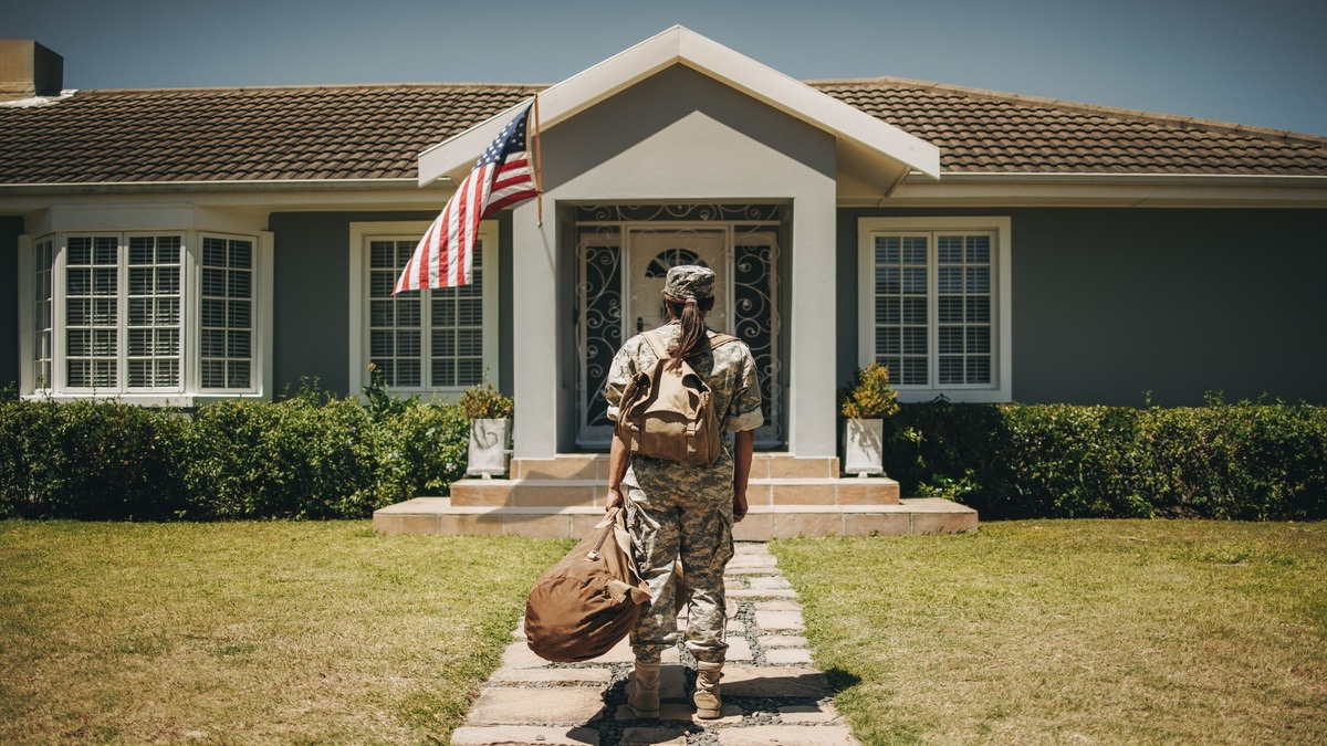 Veteran walks toward house with duffel bag in hand.