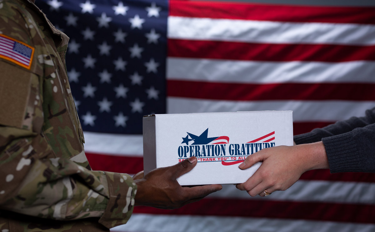 Woman hands soldier an Operation Gratitude package.